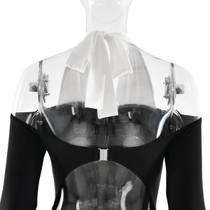 Detail view of the backless design with white halter neck strap and metal clasp on black dress
