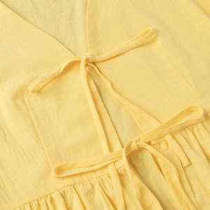 Close-up of V-neckline with double tie-up details on yellow linen texture fabric