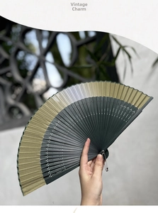 Detail of vintage Chinese folding fan with dark green fabric and carved bamboo ribs