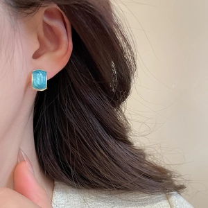 Close-up of minimalist gold rectangular stud earrings with blue enamel inlays for women