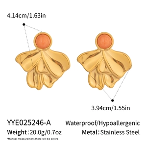 Macro detail of French vintage geometric earrings with gold texture and coral stones