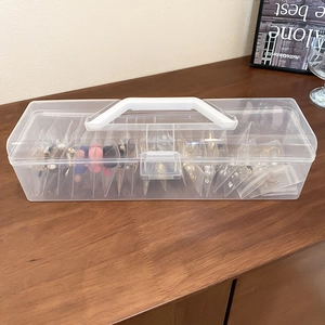 Transparent portable jewelry storage box with white handle and multi-compartment design