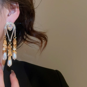 Detail of long pearl tassel earrings featuring gold heart stud and dangling crystal chains