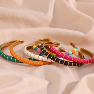 Detailed view of colorful enamel bangles with gold plating on pink satin fabric