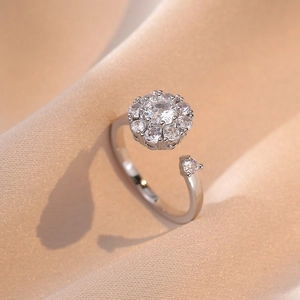 Detail view of a floral silver open ring with round clear zircon on beige silk fabric