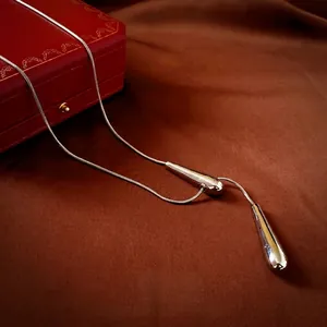 Elegant geometric teardrop pendant necklace with a polished silver-tone snake chain on a red box