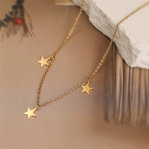 Detailed view of dainty gold star pendant necklace on natural white stone and plant