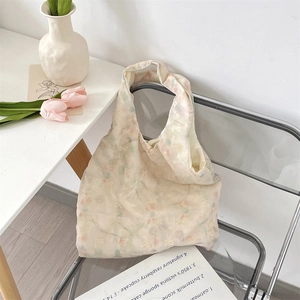 Detail of beige tote bag with delicate bow embroidery and floral texture on soft fabric
