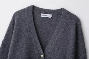 Détail d'un gilet en laine gris anthracite avec col en V et boutons en métal doré élégants