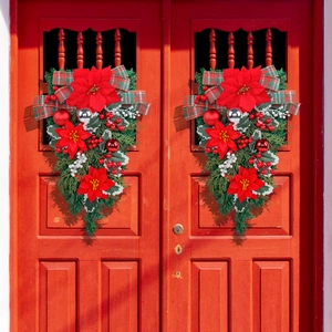 Christmas teardrop wreath with poinsettias and plaid bow on a red wooden door