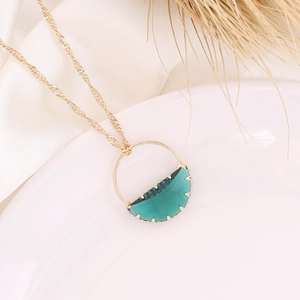 Golden chain necklace with green crescent glass pendant on elegant white silk background