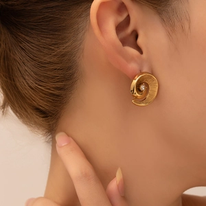Detailed view of golden spiral shell textured earrings with a center zircon stone