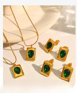 Macro detail of 18K gold-plated snake chain necklace with emerald green gemstone pendant