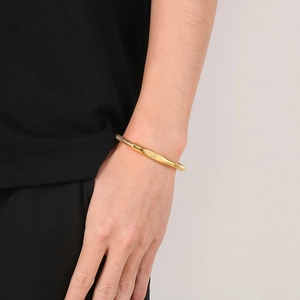 Close-up of a gold stainless steel spring bracelet on a male wrist with polished plate