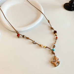 Dettaglio della collana in cuoio con perline colorate e ciondolo a cavallo a dondolo