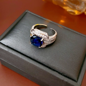 Détail d'une bague avec zircone bleue et pavé de diamants sur un écrin noir