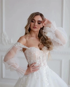 Detail of off-shoulder bridal gown with lace floral embroidery and sheer puff sleeves