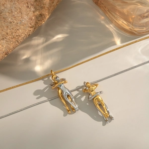 Close-up of gold and silver couple hugging pendants on stone and glass decor