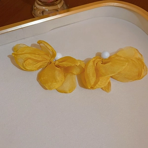 Boucles d'oreilles fleurs en tissu jaune avec perle centrale sur un plateau doré