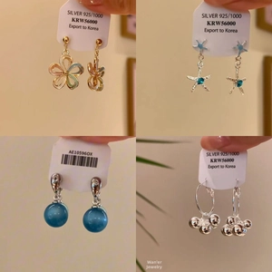 Detail view of S925 silver earrings with enamel flower and blue starfish charms