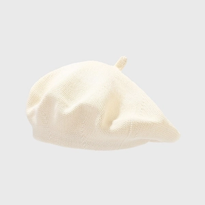 Close-up of the beige knitted cotton beret showing dense textured weave and top stem detail
