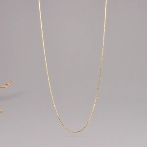 Detail view of thin gold stainless steel neck chain with polished metallic finish