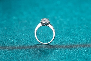 Macro shot of silver moissanite ring with halo setting and side heart cut-out detail