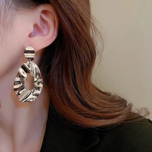 Macro shot of silver textured irregular geometric earrings with a unique crumpled metal finish