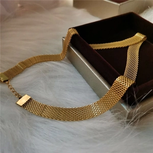 Dettaglio di una collana choker a maglia larga dorata con chiusura a moschettone su peluche