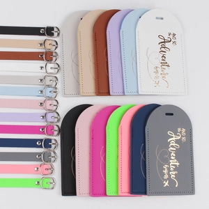 Flat lay of colorful arched PU leather luggage tags with gold adventure quotes and buckles