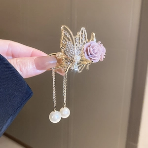 Detail of golden floral hair claw with purple rose and pearl tassel pendants