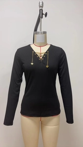 Dettaglio scollo a V con catena dorata e ciondoli a cuore su maglia nera a coste lunga