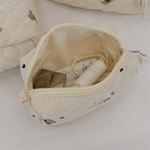 Detail of quilted corduroy makeup bag with embroidered bears and heart patterns