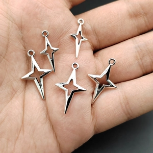Three sizes of silver star pendants displayed on palm for clear size comparison