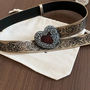 Detail of vintage heart buckle with rose relief and floral pattern leather belt