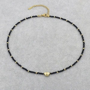 Detail of beaded necklace with black crystals and a polished gold heart pendant