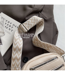 Detail eines breiten geometrischen Webgurts mit Silberschnallen an einer Brusttasche