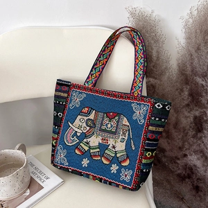 Detailed embroidery of an elephant and geometric patterns on a blue canvas tote bag