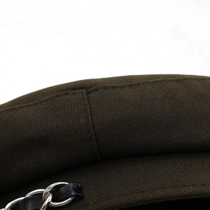 Detail of cotton newsboy hat featuring a silver chain with black leather strap decoration