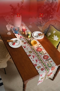 Detailed view of cream festive table runner featuring red reindeer and tassel fringe