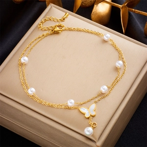 Elegant gold double-layered anklet with white pearls and a butterfly charm on a display