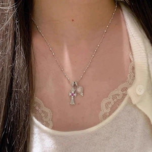 Nahaufnahme einer Halskette mit rosa Zirkonia-Kreuz und Herzanhänger auf der Haut