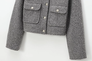 Détail du tissu en tweed gris et des boutons dorés gaufrés sur la veste courte