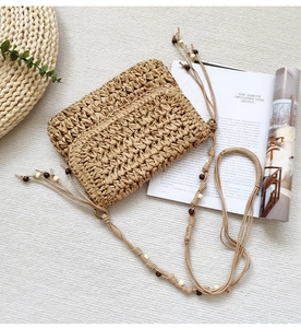 Detail of hand-woven straw crossbody bag with decorative wooden beads and rope strap