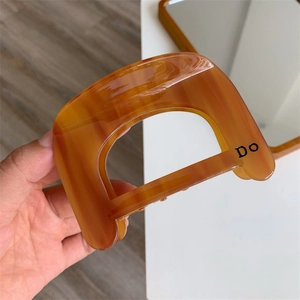Macro detail of amber acetate shark clip with DO lettering and tortoise pattern