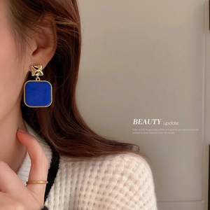 Elegant Klein Blue square drop earrings with gold metal studs worn by a female model