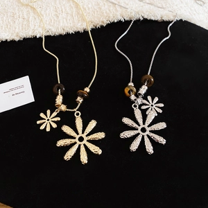 Close-up of dual flower pendants in gold and silver with tiger eye stone beads