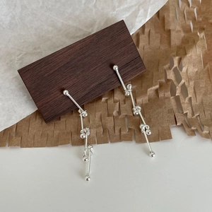 Macro detail of long minimalist 925 sterling silver dangle earrings with bar and bead design