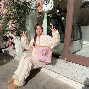 Outdoor shot of the pink quilted crossbody bag paired with a floral hooded jacket