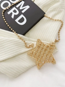 Mini star-shaped gold metallic box bag with a spherical chain on white fabric texture